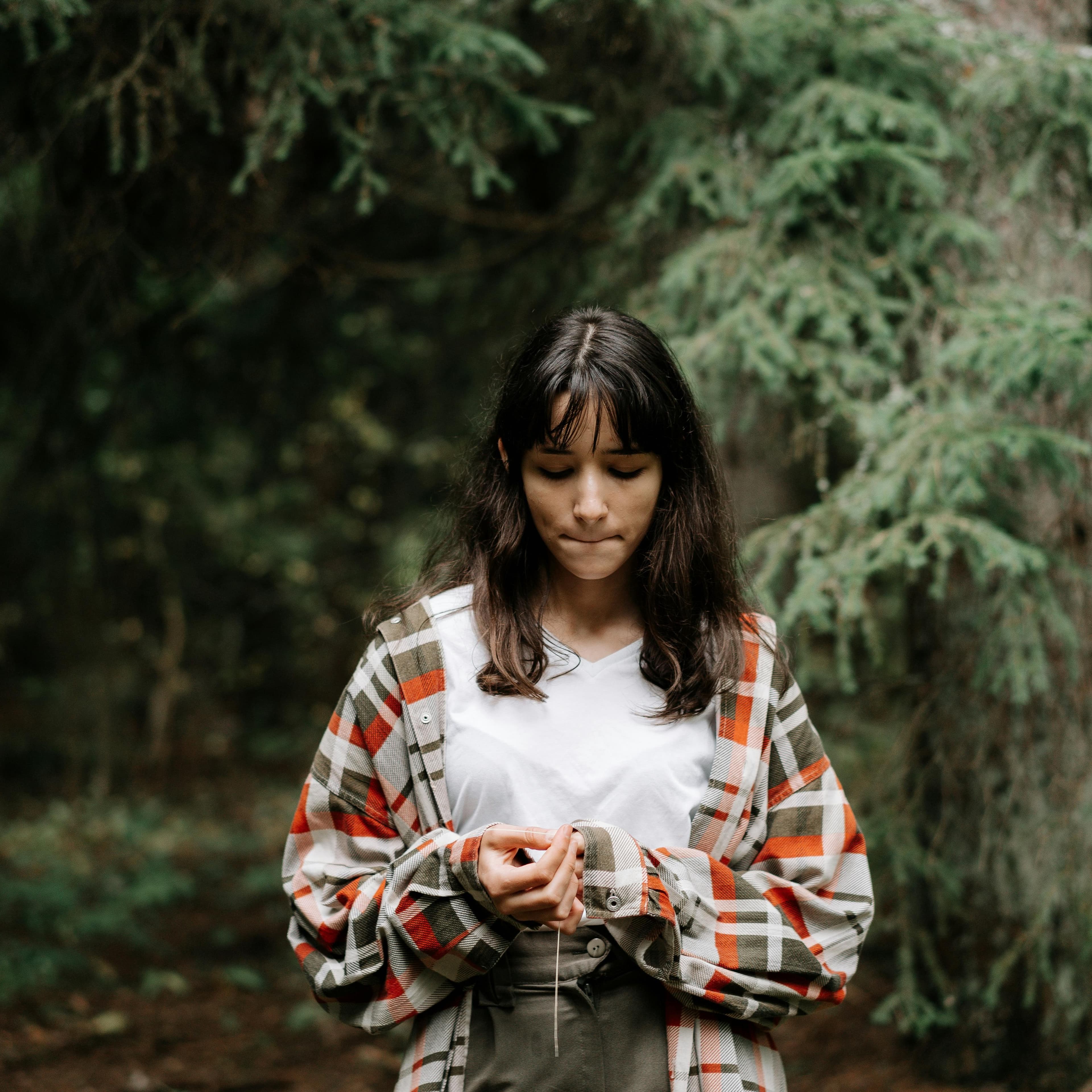Young woman in the woods looking down at her hands